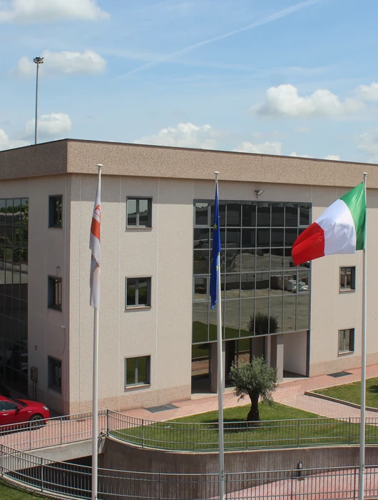 La sede di Mako Italia: palazzina uffici con facciata in vetro e bandiere davanti allo stabilimento produttivo